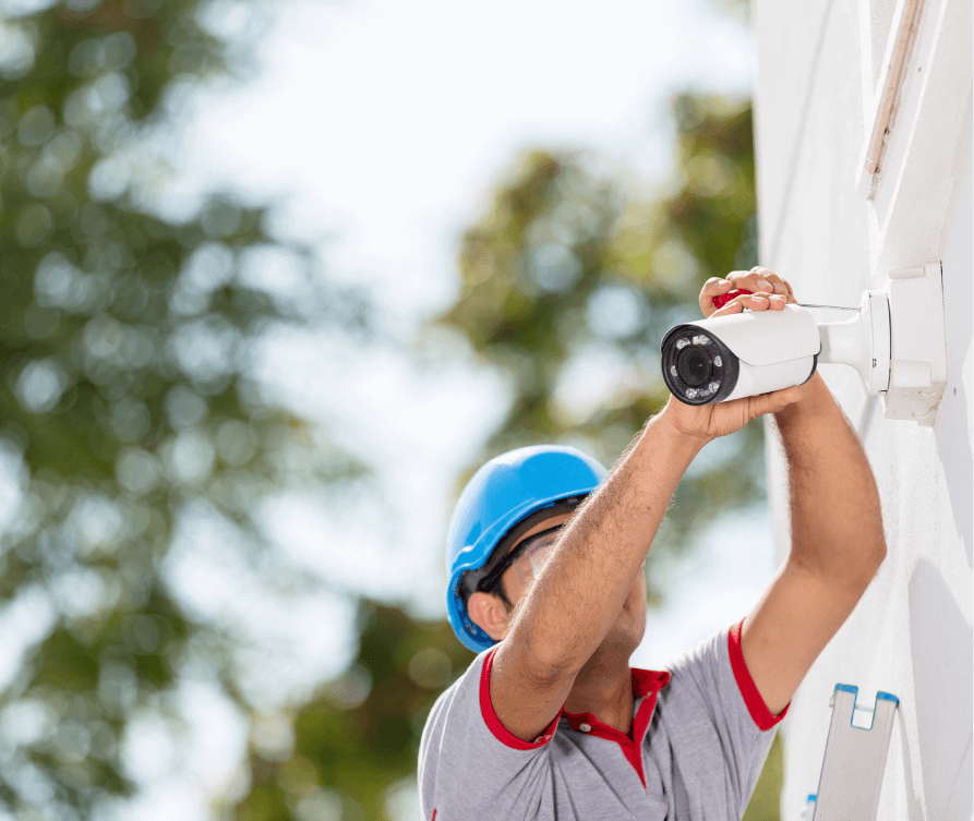 Installer securing pan tilt zoom camera mount on rooftop parapet